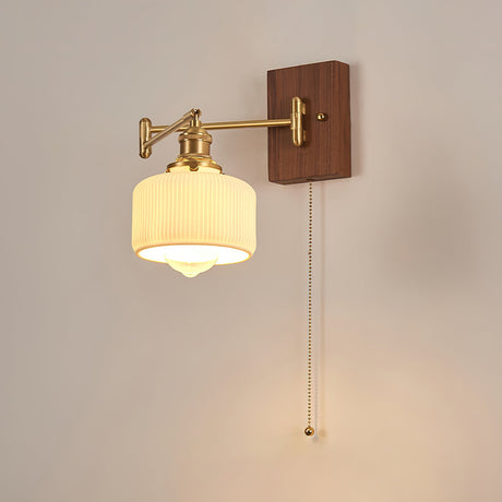 Ribbed opal drum lit warm, the pull chain hanging beside the shade