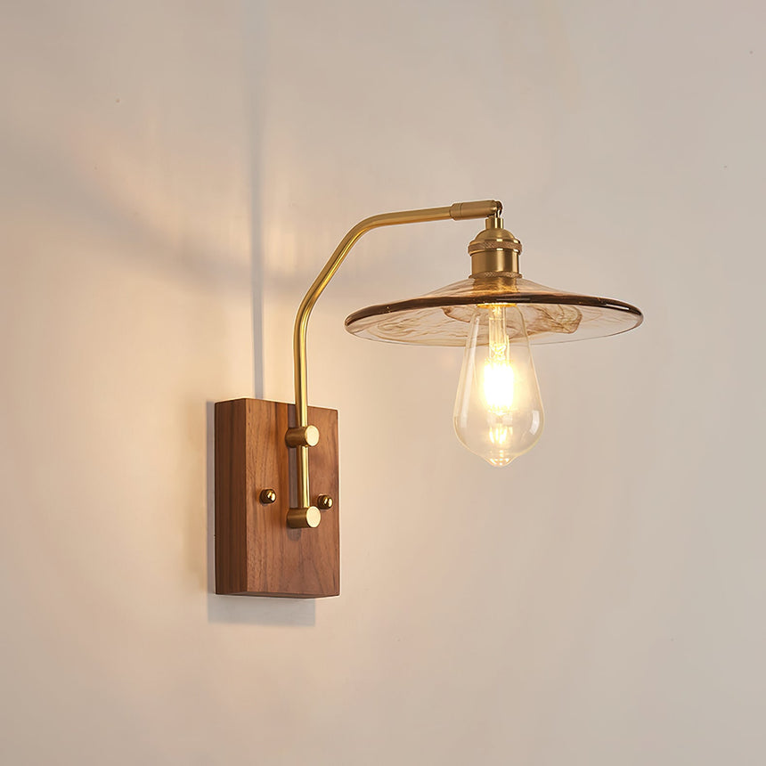 Clear glass disc shade with a filament lamp on a curved brass arm
