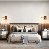 A pair of brass and walnut sconces lit above a slatted wood headboard