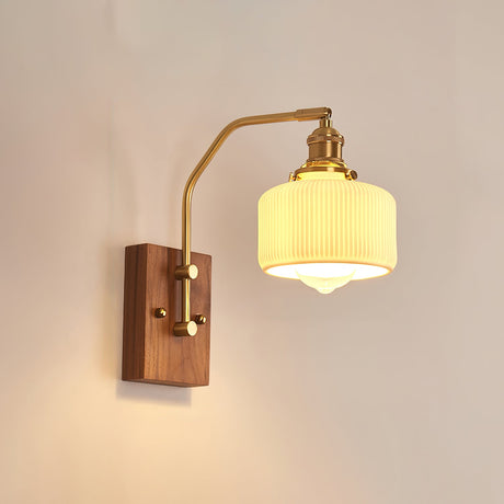 Ribbed opal glass drum lit warm on a brass arm and walnut backplate