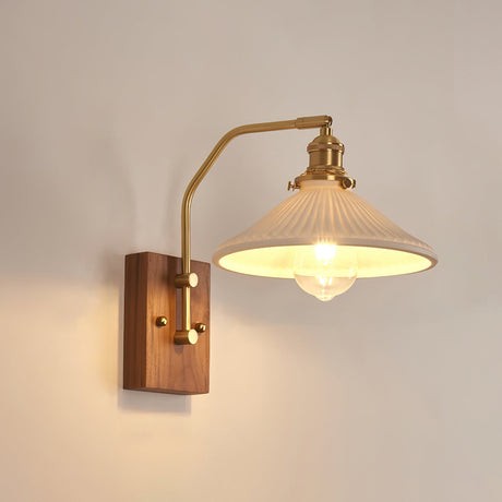 Wide ribbed glass cone lit beside a walnut plate and brass fittings
