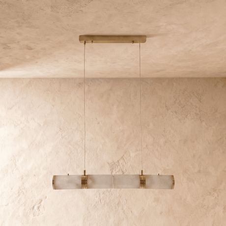 The same stone tube unlit, pale cylinders and brass collars on a plaster wall
