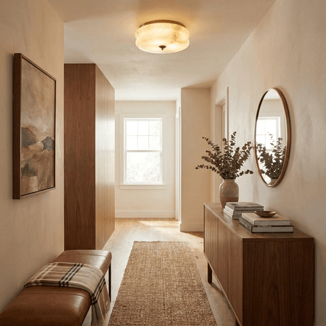 Scalloped alabaster ceiling light in a hallway with a round mirror and a console