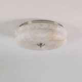 Nickel trim alabaster ceiling light seen close up against a plain background