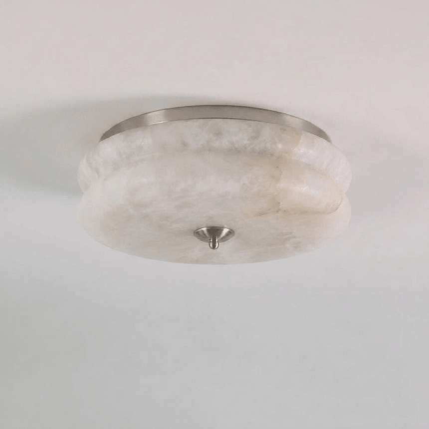 Nickel trim alabaster ceiling light seen close up against a plain background