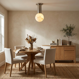 Alabaster sphere ceiling light above a round dining table with pale upholstered chairs