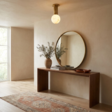 Alabaster sphere ceiling light in a hallway with a round mirror and a wood console