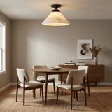 Alabaster cone ceiling light above a dining table with upholstered chairs and a sideboard