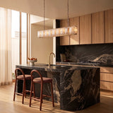 A lit stone cage above a kitchen island with two stools