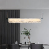 A lit stone bar over a dining table with chairs and a plant beside a slatted wall