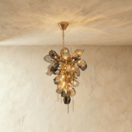 A cluster of sculpted amber and smoke glass petals with fine brass spikes below