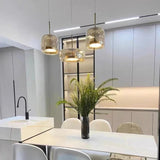 Two amber bell pendants lit above a counter with a large plant