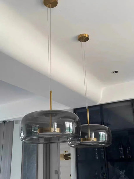 Two smoke gray bell pendants lit side by side above a counter
