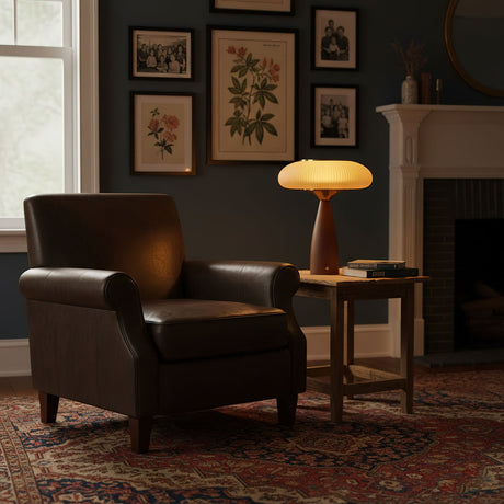 Amber glass table lamp lit on a side table beside a leather armchair