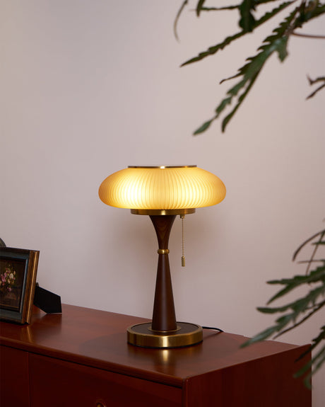 Amber glass table lamp lit on a red toned dresser with a frame