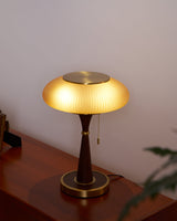 Amber glass table lamp lit on a wood chest beside a plant