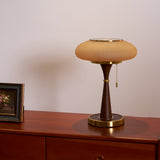 Amber glass table lamp lit on a wood dresser beside a photograph