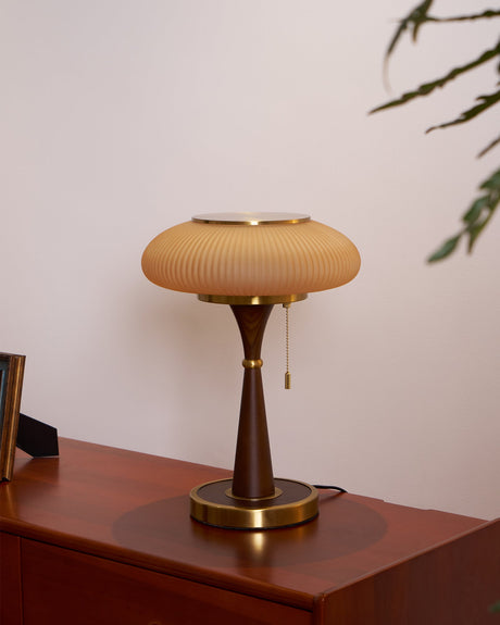 The white glass version lit on a console beside a framed picture