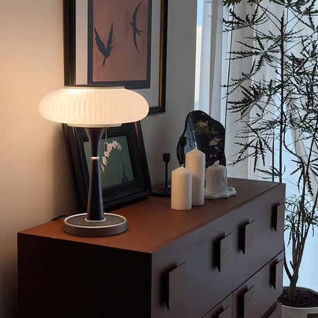 The white glass version lit on a dark cabinet beside candles