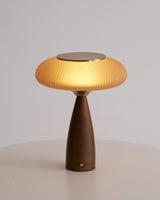 Amber glass table lamp seen from the front against a plain ground