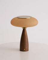 Amber glass table lamp lit and seen in full against a plain ground