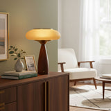 Amber glass table lamp lit on a walnut sideboard beside a vase