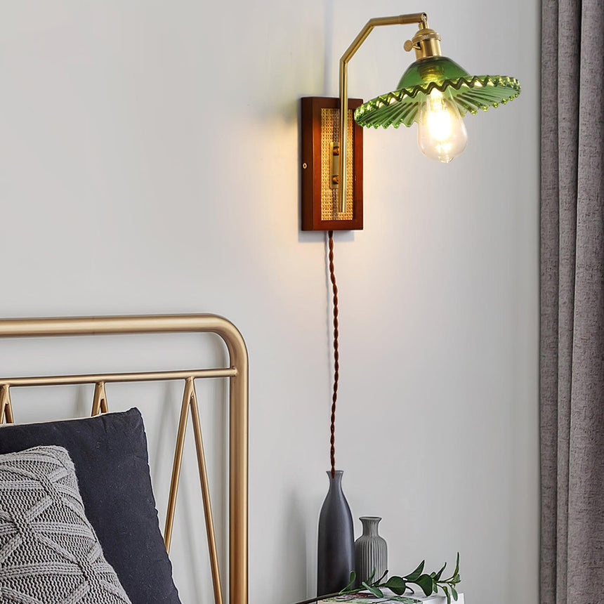 The sconce with a green shade lit above a bed with a metal headboard