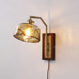 The amber drum glass shade lit on a plain wall