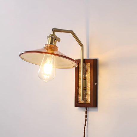 The flared amber glass shade lit on a plain wall