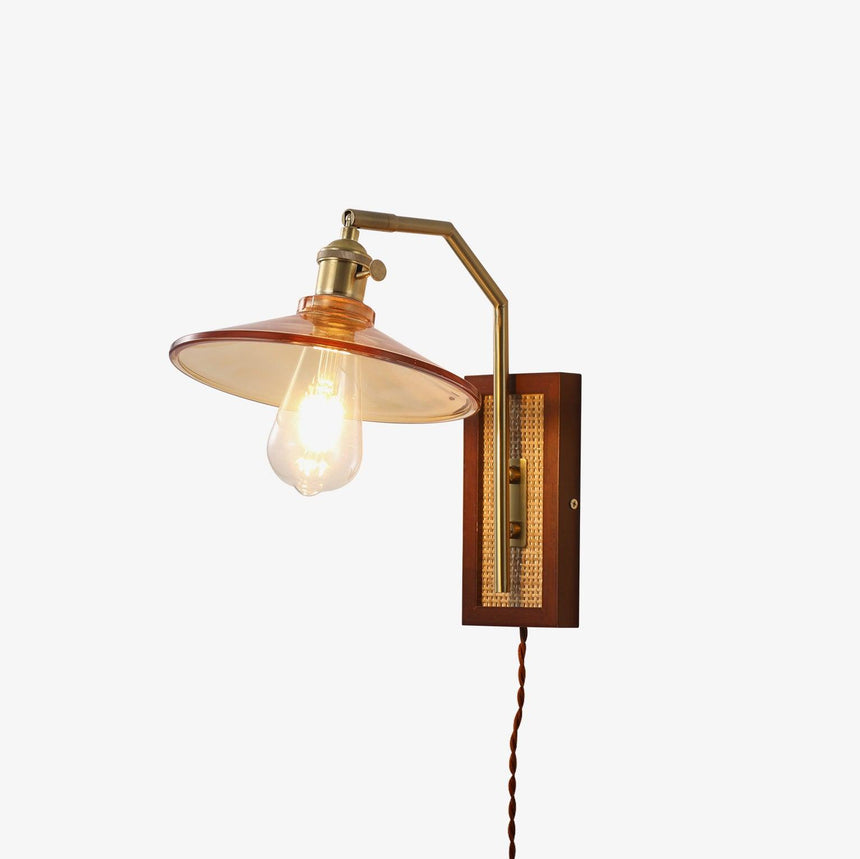 Plug-in sconce with a walnut and cane back plate, a copper arm and an amber glass shade