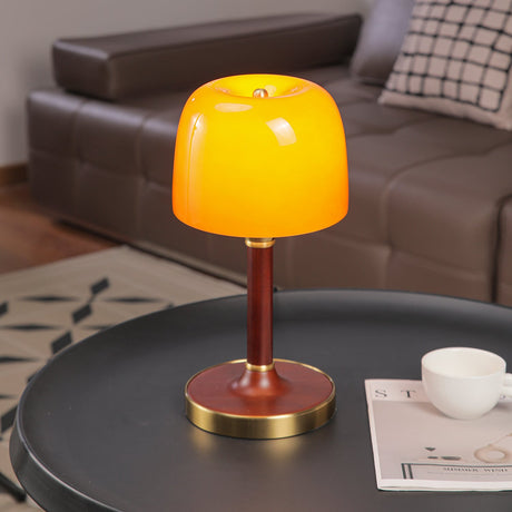 Amber table lamp lit on a round table beside a cup and a book