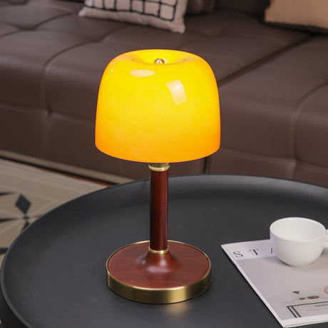 Amber table lamp lit close, the tinted glass dome glowing