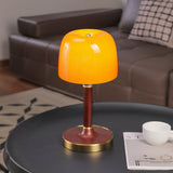 Amber table lamp lit on a round dark table beside a cup