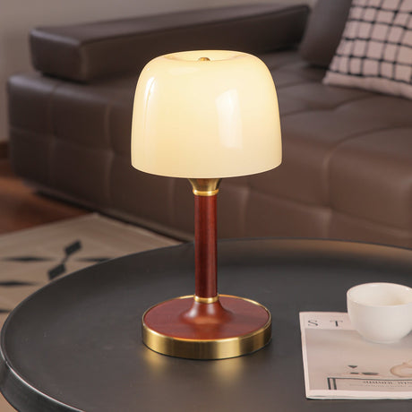 The white glass version of the table lamp lit on a dark table