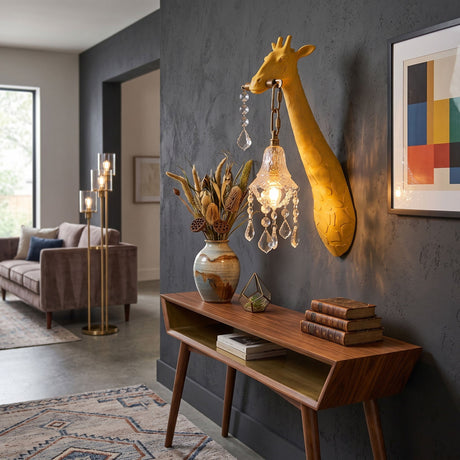 The yellow giraffe sconce lit on a dark wall above a wood console with a vase