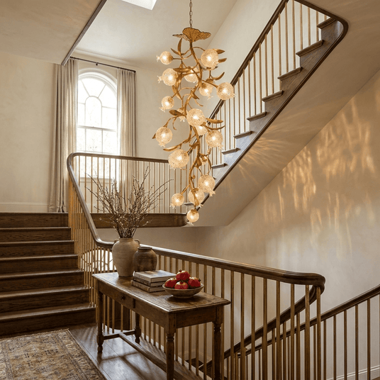 Brass branch chandelier lit above a staircase beside a console table