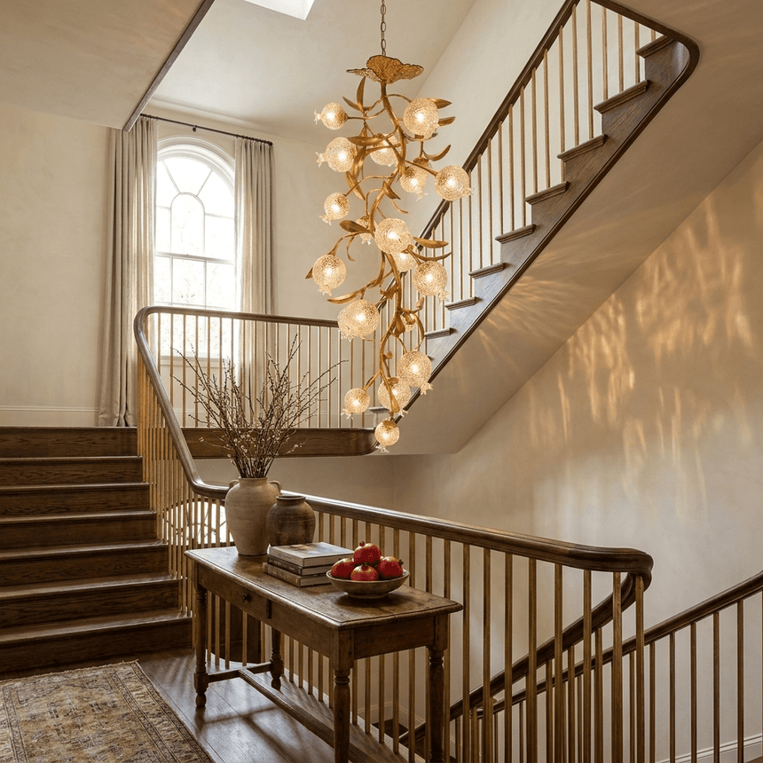 Brass branch chandelier lit above a staircase beside a console table