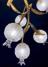 Close view of four frosted globes hanging from their brass stems