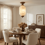 Antique brass stone ceiling light lit above a round dining table with pale chairs