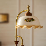 Close view of the arched brass arm and the painted glass bell shade