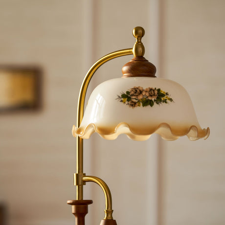 Close view of the arched brass arm and the painted glass bell shade