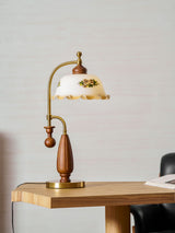 Antique brass table lamp lit on a table beside a pale curtain