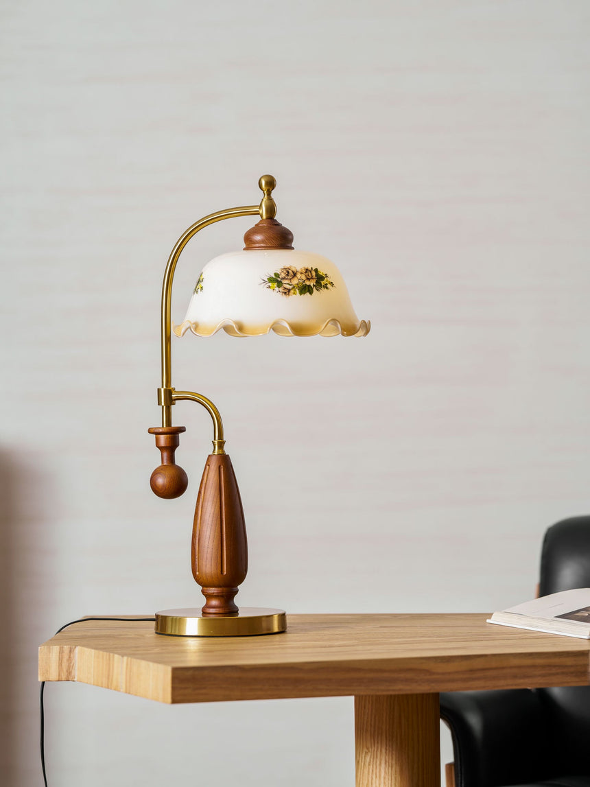 Antique brass table lamp lit on a table beside a pale curtain