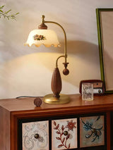 Antique brass table lamp lit on a chest beside framed pictures