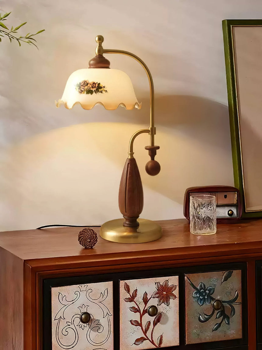Antique brass table lamp lit on a chest beside framed pictures