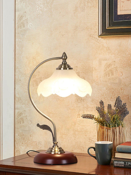 Flower shade lamp lit on a console beside a cup and lavender