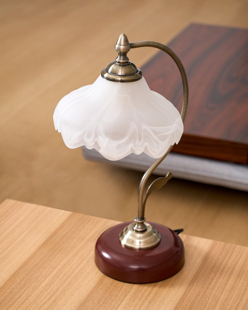 Flower shade lamp unlit on a wood desk against a dark cabinet