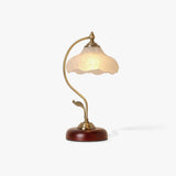 Frosted flower shade lamp seen from an angle, unlit, on a wood base
