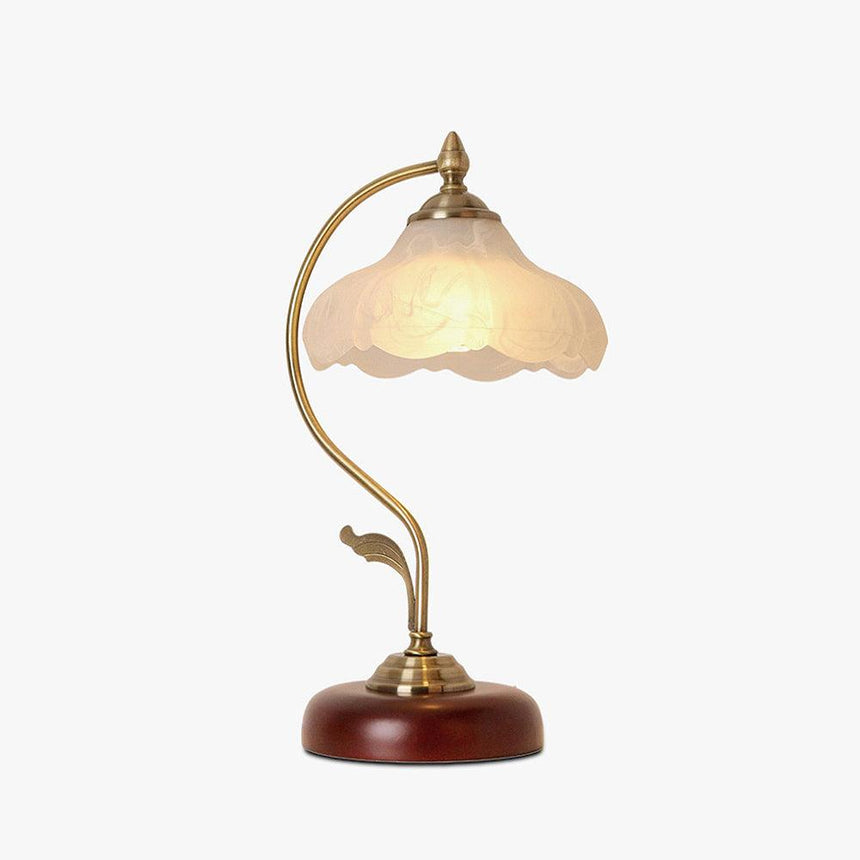 Frosted flower shade lamp lit on a plain ground, the arm curving over