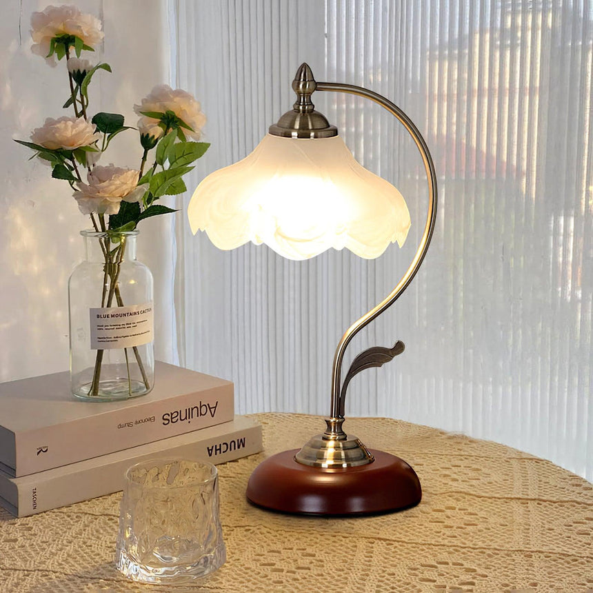 Flower shade lamp lit beside white daisies and a stack of books